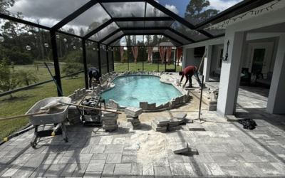 Workers installing pavers around a pool in a Southwest Florida backyard, showcasing paver installation process for outdoor spaces.