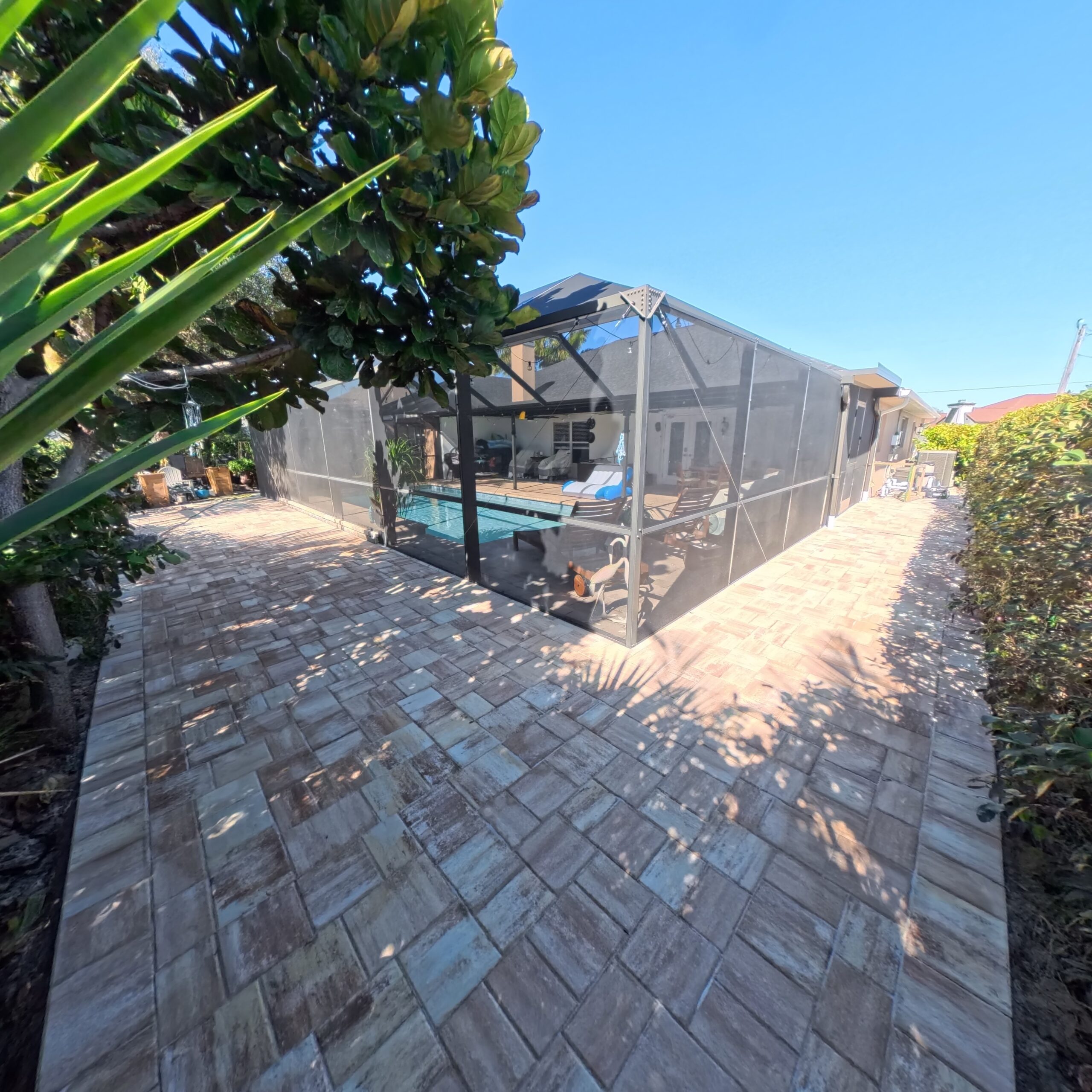 IMG_20260203_131036_372 Paver walkway leading to a screened pool area surrounded by lush greenery, showcasing Elite Pavers Solutions' craftsmanship in outdoor renovations in Southwest Florida.